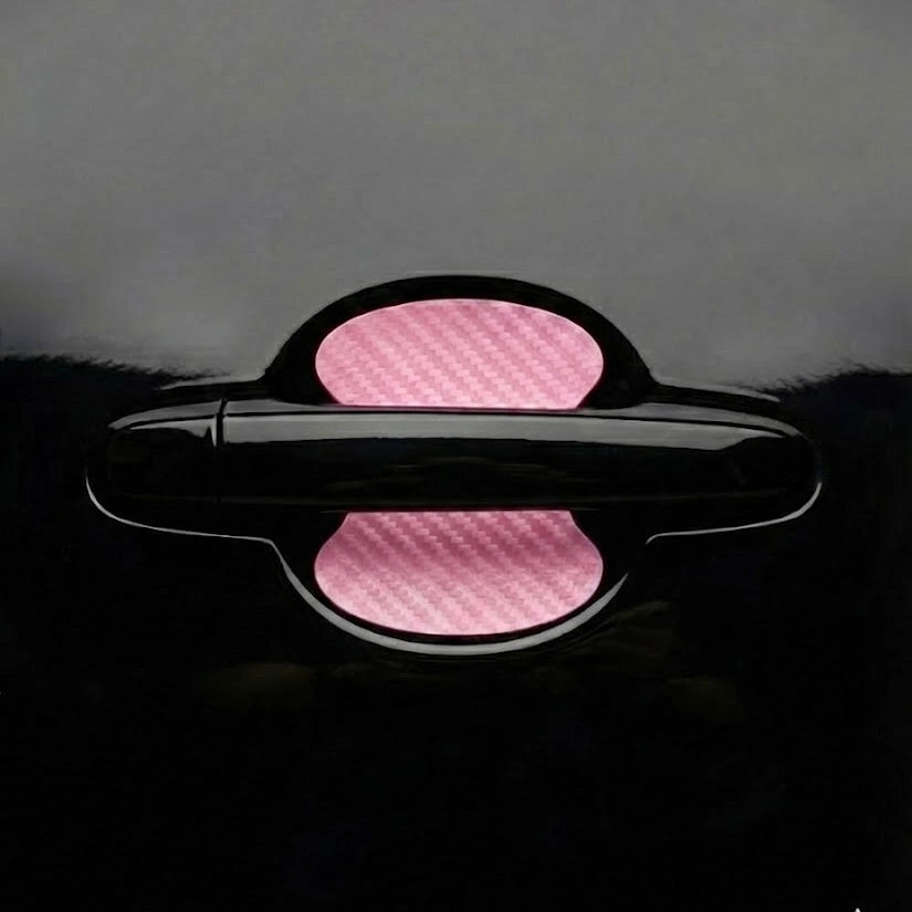 Pink carbon fiber car door handle scratch protector sticker applied on black car door. A unique Car-Wah! car accessory statement piece that adds instant personality.