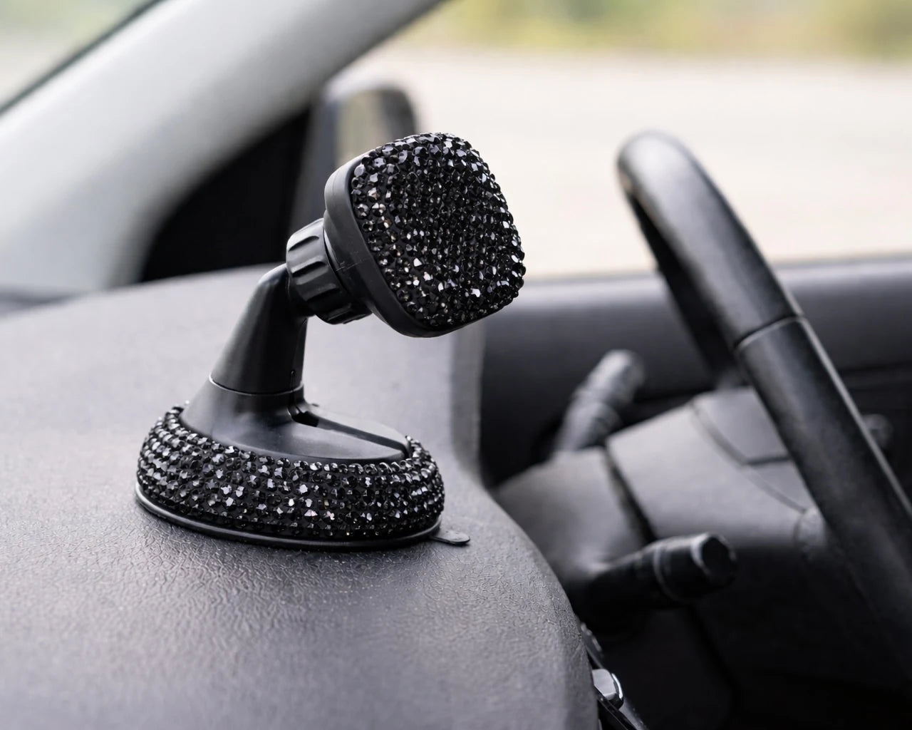 Black bling car phone holder mounted on dashboard. Close-up macro detail of the sparkling crystals on the bling car mobile holder, a playful Car-Wah! statement piece