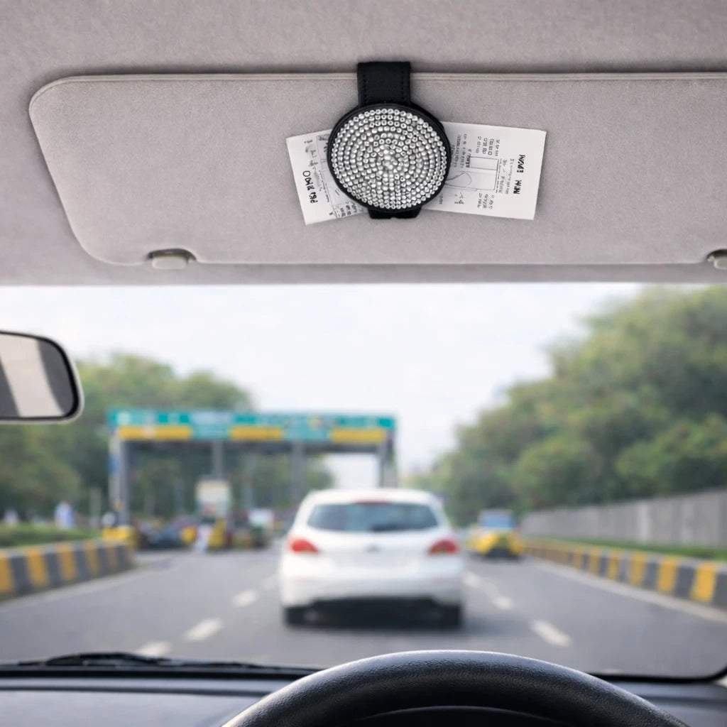 Silver magnetic sunglasses holder clipped to car visor holding parking tickets. A practical and aesthetic car accessory by  Car-Wah! to keep your world on wheels organized.